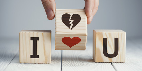 Hand flipping a wooden cube to remove the red heart for the broken heart or vice versa on neutral...