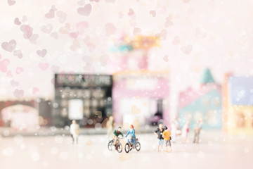 Happy young couple  (miniature) on cycle ride (miniature) on cycle ride in the city.Valentine's day background with selective focus and soft pastel color toned.