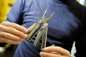 knife multitool turned into pliers in the hands of a man.
