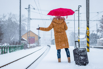 Woman is waiting at the railroad station for a delayed train during snowstorm. 