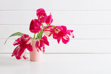 pink tulips in vase on white wooden background