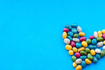 heart of multicolored candies on blue background