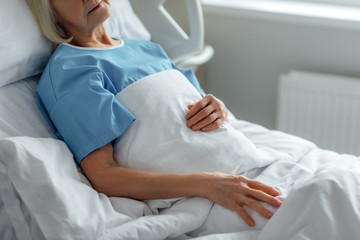 Obraz na płótnie Canvas cropped view of senior woman lying in hospital bed