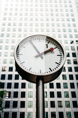 Fototapeta na wymiar Street clock with tall building on the background