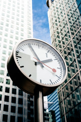 Fototapeta na wymiar Street clock with tall building on the background