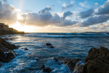 Waves by a rocky shore in Alghero at sunset