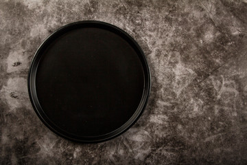 Black dish on a gray background. Layout of black dishes on a gray background. View from above.