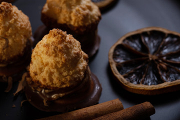 Few pieces of baked sweets on dark plate with orange rings