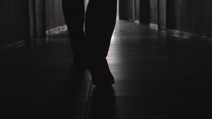 Dolly with low-section of silhouette of legs of man walking along hallway towards the camera - Powered by Adobe