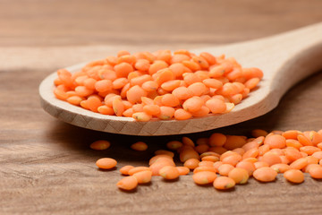 Lentejas naranjas crudas en una cuchara de madera, detalle