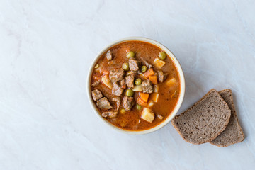 Tasty Hungarian Hot Goulash Soup Bograch or Gulas Lamb Meat Stew with Whole Grain Bread on Wooden...