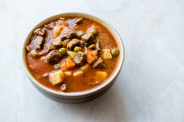 Tasty Hungarian Hot Goulash Soup Bograch or Gulas Lamb Meat Stew with Whole Grain Bread on Wooden Surface at Restaurant. Traditional Food.
