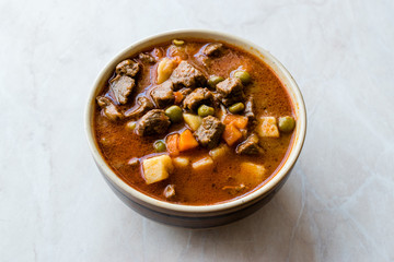 Tasty Hungarian Hot Goulash Soup Bograch or Gulas Lamb Meat Stew with Whole Grain Bread on Wooden Surface at Restaurant. Traditional Food.