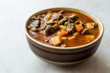 Tasty Hungarian Hot Goulash Soup Bograch or Gulas Lamb Meat Stew with Whole Grain Bread on Wooden Surface at Restaurant. Traditional Food.