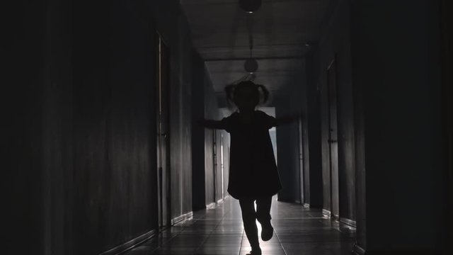 Silhouette of playful little girl with two ponytails jumping the rope towards the camera along hallway
