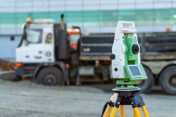 Obraz premium Surveyor equipment (theodolite) on construction site of the airport, building or road with construction machines in background