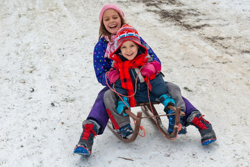 Children enjoy snowshoeing in the snow park where the grass comes out