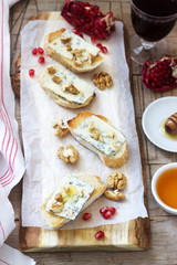 Sandwiches with blue cheese, pomegranate, honey and nuts served with red wine. Rustic style.
