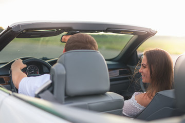 Naklejka premium Young couple has a vacation driving a white cabriolet