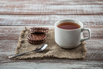 Chocolate chip cookies and a mug of tea on a white wooden table.