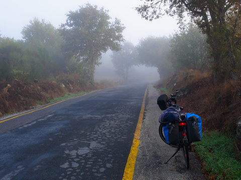 Bicicleta de cicloturismo con alforjas en una carretera secundaria con niebla