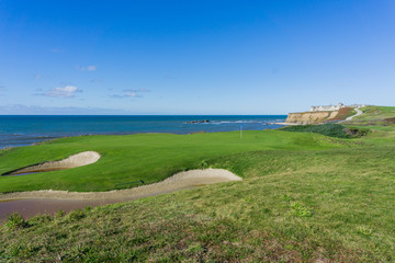 Golf course putting green on the cliffs by the pacific ocean, Resort in the background, Half Moon Bay, California