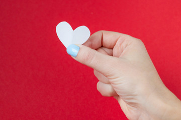 hand holding a white heart on a red background. Background for Valentine's day.the eighth of March,place for text