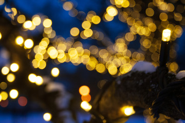 Fototapeta na wymiar Abstract background yellow bokeh lights, branches of a tree in winter with blue sky and snow, natural landscape, warm feeling, warmth 