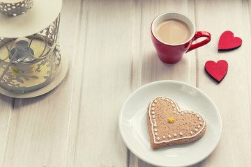 Love concept. Female hands holding a cup of coffee, red heart in a box on a wooden table. Top view.