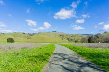 Gravel trail leading to the green hills and valleys in Coyote Lake - Harvey Bear Park, Morgan Hill, California