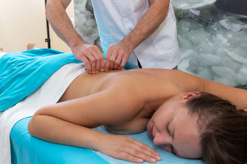 Osteopath massages the patient on her back. Tightening the skin.