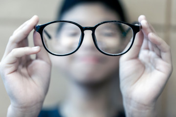The Black frame glasses on the hands of boys with short-sighted eyes in front.Concepts of short-sighted children from playing games all the time.