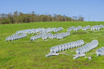 Ceramic insulators spread on a green meadow waiting to replace old ones, California