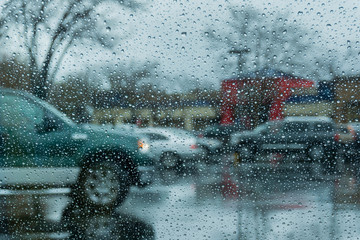 Drops of rain on the window; parked cars in the background; shallow depth of field