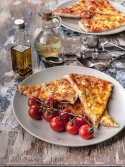 Tasty pizza and cherry tomatoes on a plate on a wooden table. Vertical shot. Mediterranean Kitchen