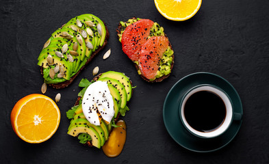breakfast with avocado, sesame, grapefruit, orange, egg, coffee on a concrete black background