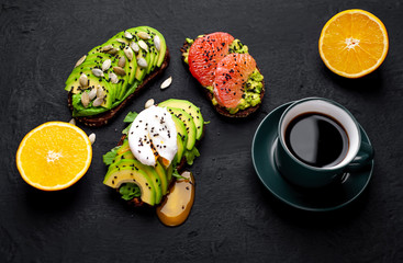 Fototapeta na wymiar breakfast with avocado, sesame, grapefruit, orange, egg, coffee on a concrete black background
