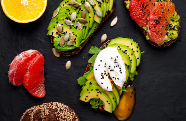 breakfast with avocado, sesame, grapefruit, orange, egg on a concrete black background