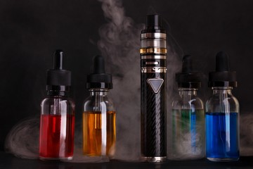 Obraz na płótnie Canvas Electronic cigarette and bottles with vape liquid within vapor on black background
