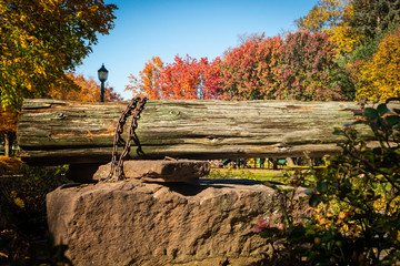 Naklejka na ściany i meble Stone and wooden log structure in a park on a sunny autumn day