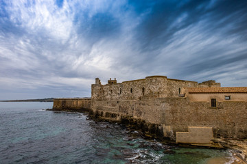 Fototapeta na wymiar Middle Aged Maniace Castle on seacoast in island of Ortigia on Sicily, Siracusa.