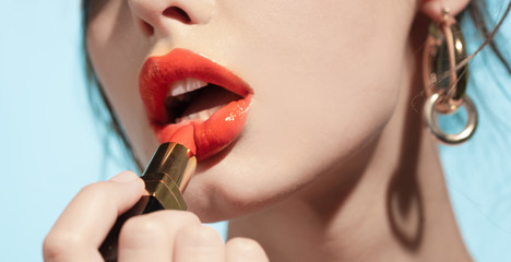 Girl paints her lips with lipstick - obrazy, fototapety, plakaty