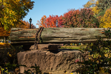 Fototapeta premium Stone and wooden log structure in a park on a sunny autumn day
