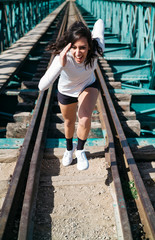 Young woman running through the railroad