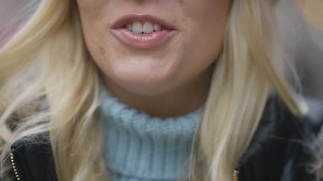 Mouth of a young blonde female talking directly to camera