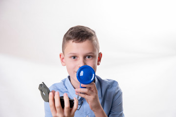 Fototapeta premium Boy explains the way with a blue megaphone and a compass in hand against a white background