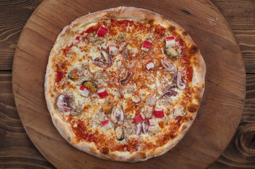 Fresh italian seafood pizza on wooden background, top view