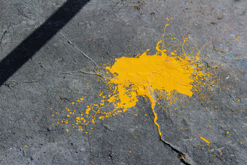 Sprayed dried yellow paint on cracked asphalt