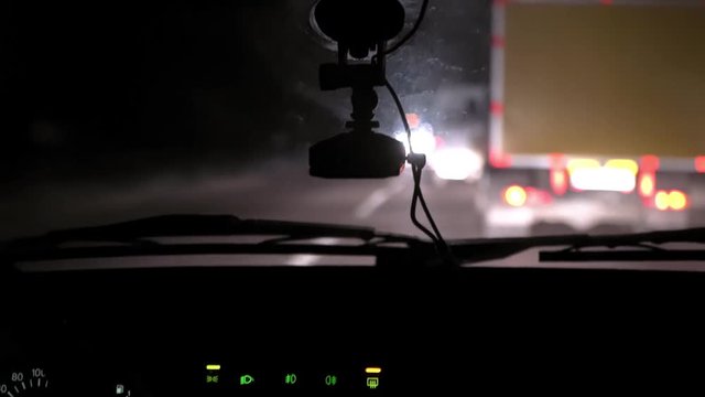 Car rides on the night road. Inside view. Dashboard, radio, DVR. Overtaking. Oncoming cars blind eyes. Headlights light the way. Road signs and markings. Traffic Laws. Track out of town