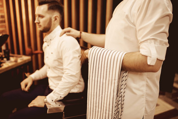 Hairdresser wagon pats on shoulder of client man as sign completion haircut